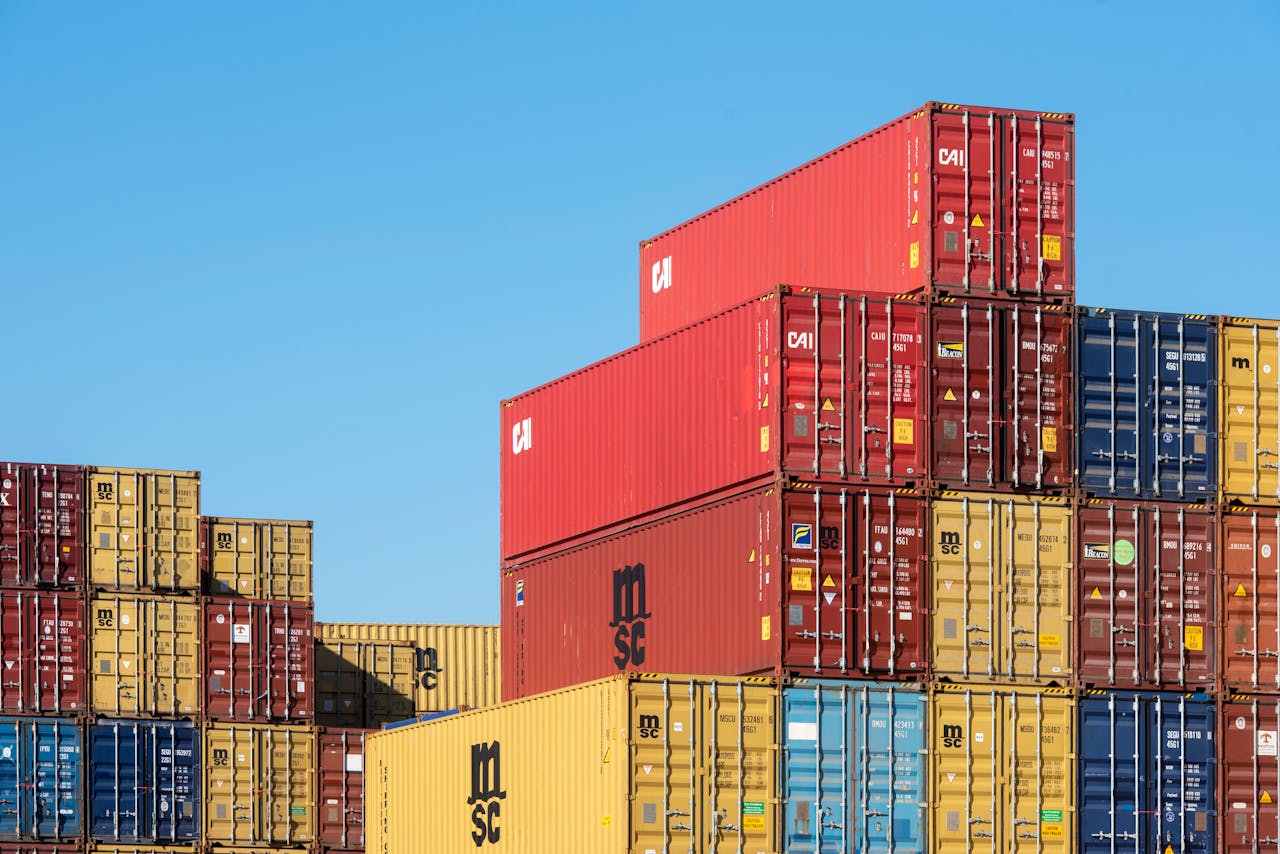 A vibrant collection of stacked shipping containers under a clear, blue sky. Ideal for logistic themes.
